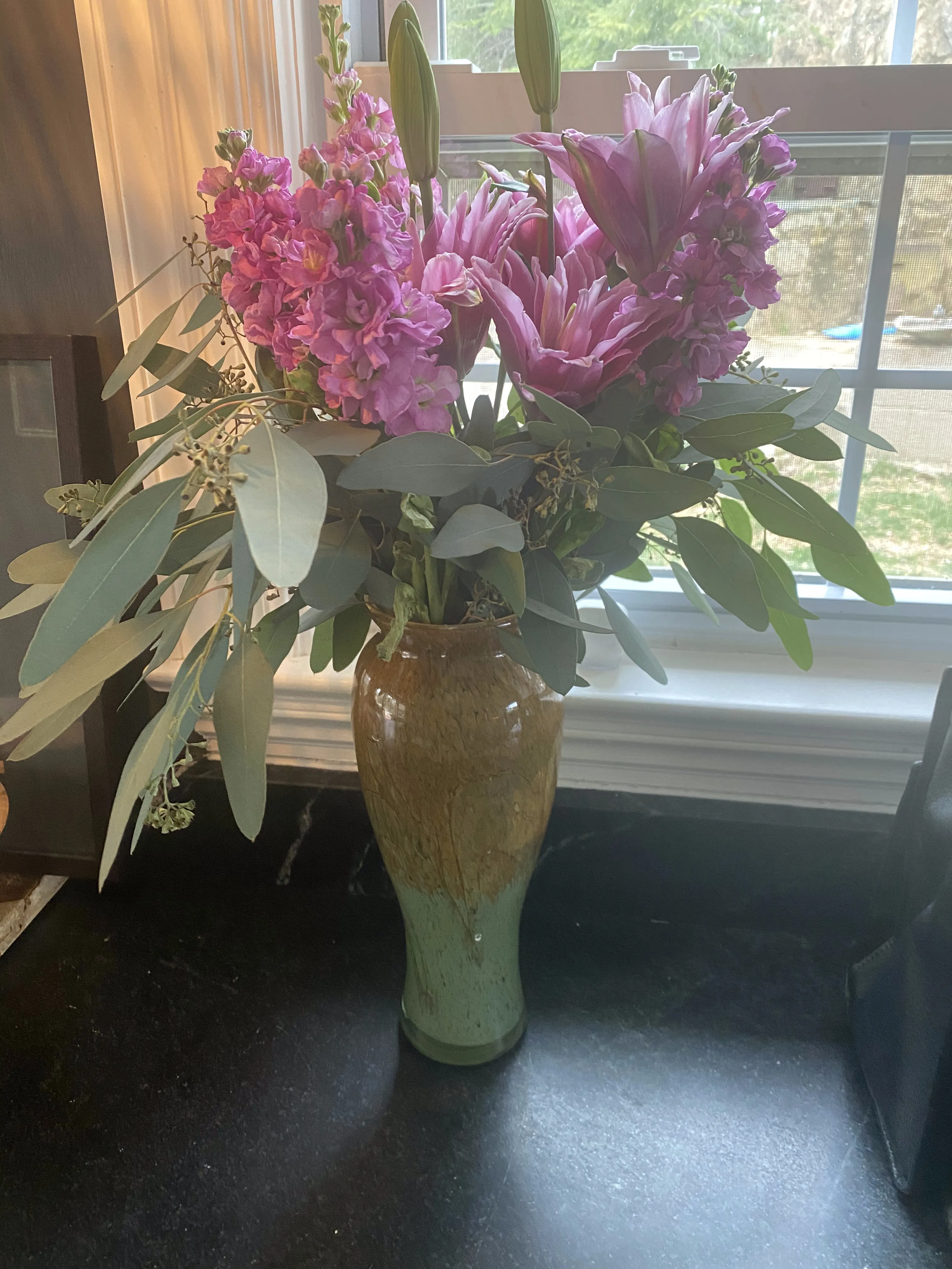 Mixed flower arrangement in a vase by the window